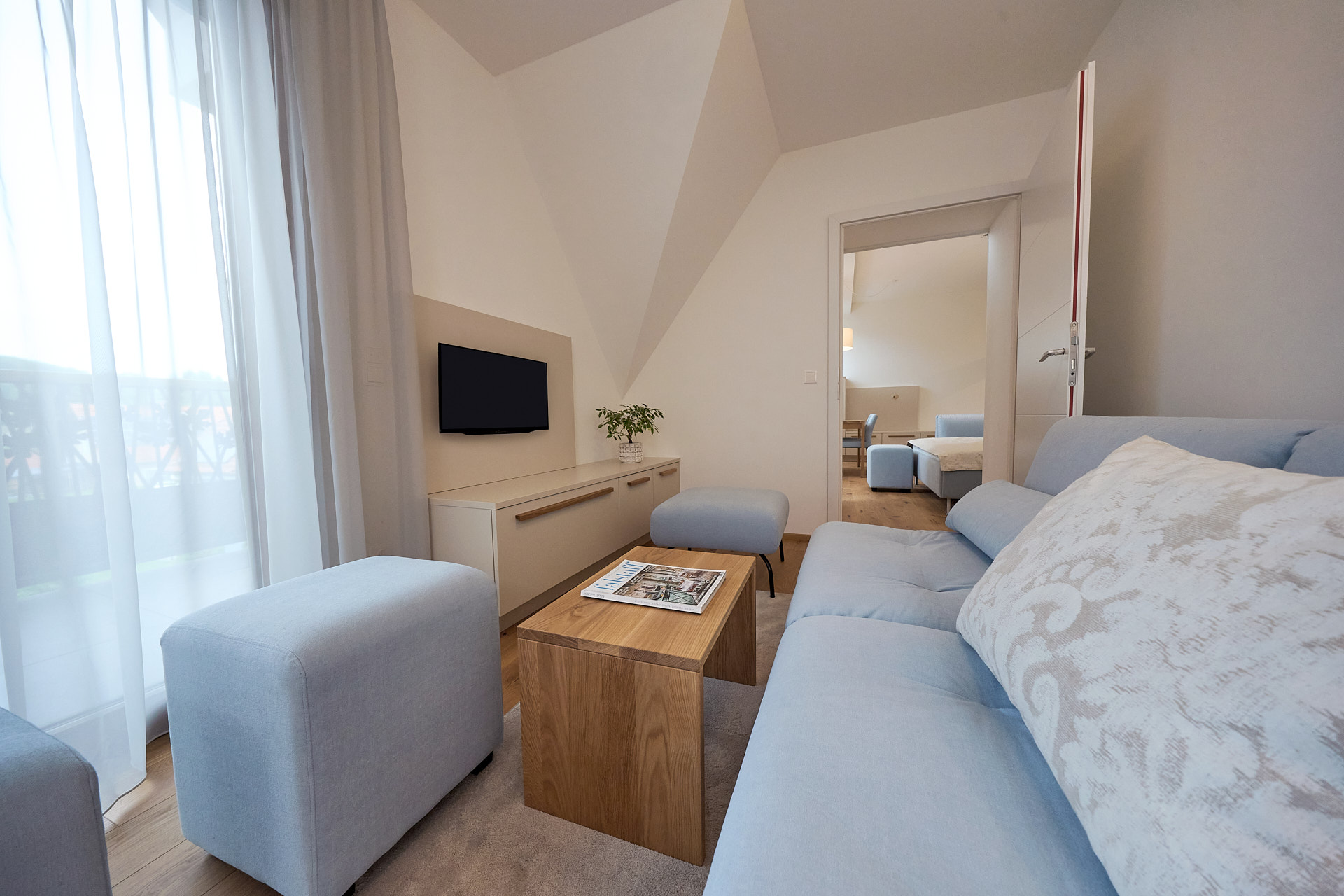 Der Wohnbereich eines Zimmers von zuHaus Gamlitz, blaues Sofa und beige Möbel.