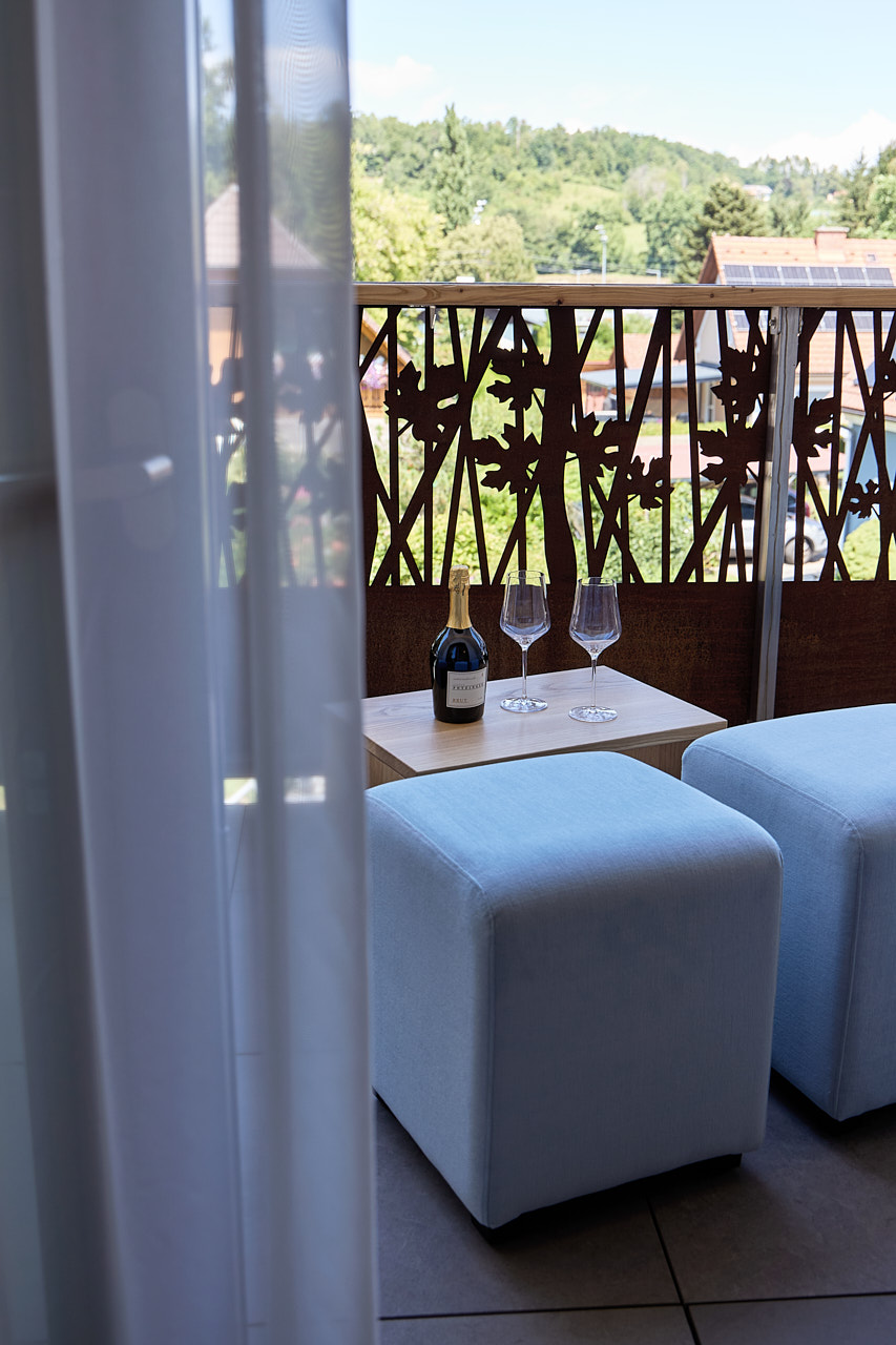 Der Balkon eines Apartments mit einer Flasche Sekt und zwei Gläsern am Tisch.